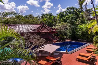 an outdoor swimming pool with chairs and an umbrella at Sarinande Hotel in Seminyak