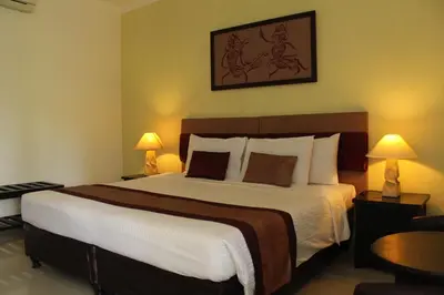 a bedroom with a large bed with two lamps at Sarinande Hotel in Seminyak