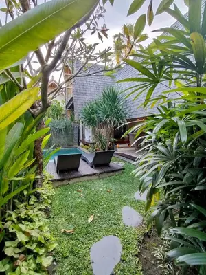 a garden with palm trees and plants in a building at Villa Made East in Seminyak