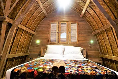 a bedroom with a bed in a wooden room at Villa Made East in Seminyak