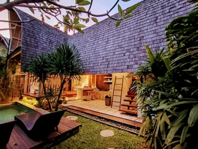 a house with a blue tile roof with a pool at Villa Made East in Seminyak