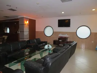 a living room with black leather furniture and three circular mirrors at Bali Paradise City Hotel in Denpasar