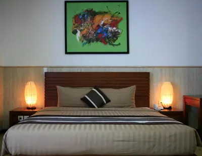 a bedroom with a large bed with two lamps at Bali Paradise City Hotel in Denpasar