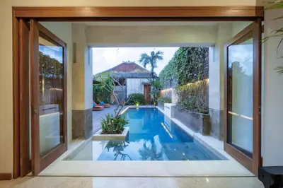an indoor swimming pool with a view of a house at Villa Artisane in Seminyak