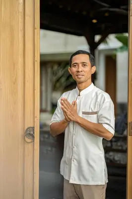 a man in a white shirt standing next to a door at Villa Artisane in Seminyak