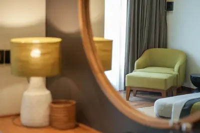 a room with a mirror and a green chair and a lamp at Villa Artisane in Seminyak