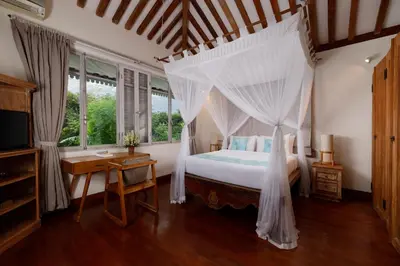 a bedroom with a canopy bed and a desk at Villa Hasian Jimbaran in Jimbaran