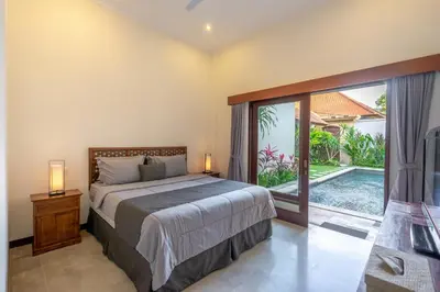 a bedroom with a bed and a sliding glass door at Amandaru Villa by RPM in Legian