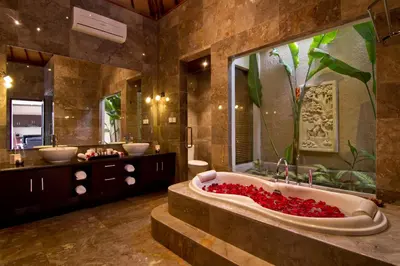 a bathroom with two sinks and a tub with red flowers at My Villas In Bali in Seminyak