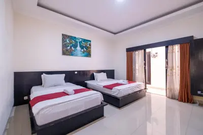 a bedroom with two beds and a window at Samudra Homestay in Kuta