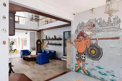 a living room with a wall painting of a man with a spear at RedDoorz Plus @ Mahendradatta Denpasar in Denpasar