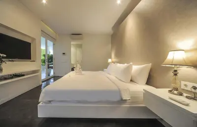 a white bedroom with a large bed and a television at Casa Priya Petitenget in Seminyak