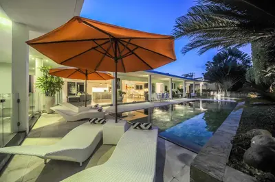an outdoor patio with a pool and an orange umbrella at Casa Priya Petitenget in Seminyak