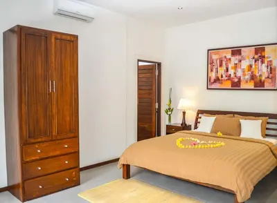 a bedroom with a large bed with a dresser and a dresser at Seminyak Villa Lumina in Seminyak