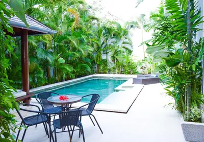 a patio with a table and chairs next to a pool at Seminyak Villa Lumina in Seminyak