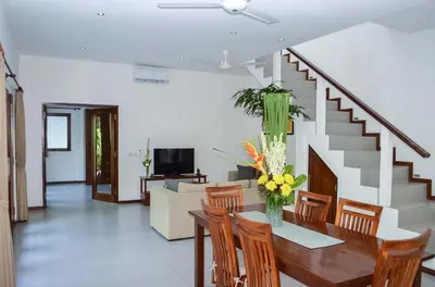 a living room with a table and chairs and a staircase at Seminyak Villa Lumina in Seminyak