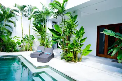 a villa with a swimming pool and palm trees at Seminyak Villa Lumina in Seminyak