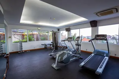a gym with treadmills and ellipticals in a room with windows at THE 1O1 Bali Fontana Seminyak in Legian