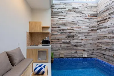 a living room with a swimming pool and a brick wall at Paisa Seminyak Living in Seminyak