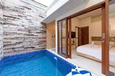 a guest room with a swimming pool and a bedroom at Paisa Seminyak Living in Seminyak