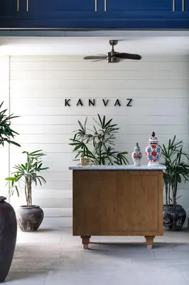 a dresser in front of a white wall with plants at Kanvaz Village Resort Seminyak in Seminyak