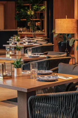 a long wooden table with plates and glasses on it at Kanvaz Village Resort Seminyak in Seminyak