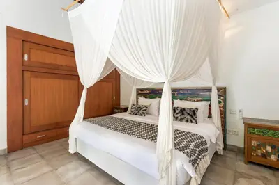 a bedroom with a canopy bed with white drapes at Villa Cinta Umalas in Canggu