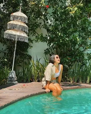 a woman sitting next to a swimming pool at The Lagoon Canggu in Canggu