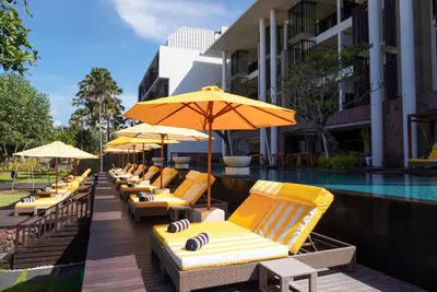 a row of lounge chairs with umbrellas next to a pool at Grand Seminyak Lifestyle Boutique Bali Resort in Seminyak
