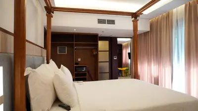 a bedroom with a bed with white sheets and pillows at Truntum Kuta Bali in Kuta