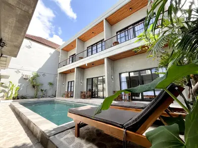 a swimming pool in front of a house at Adi surya guest house in Seminyak