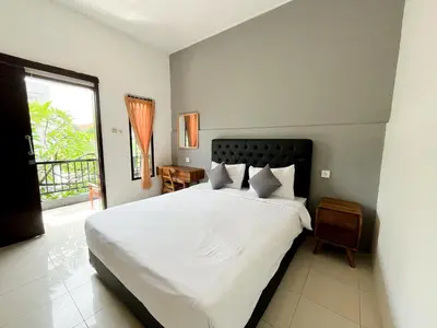 a bedroom with a large white bed and a window at Adi surya guest house in Seminyak