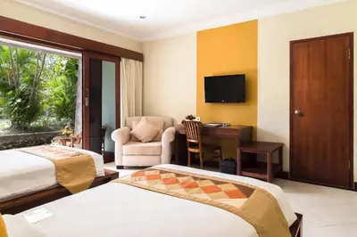 a hotel room with two beds and a desk and a chair at Hotel Vila Lumbung in Seminyak
