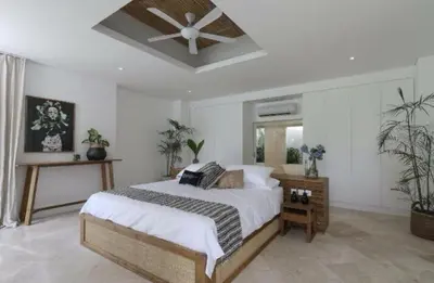 a bedroom with a bed with a ceiling fan at The Plantation at Batu Belig in Canggu