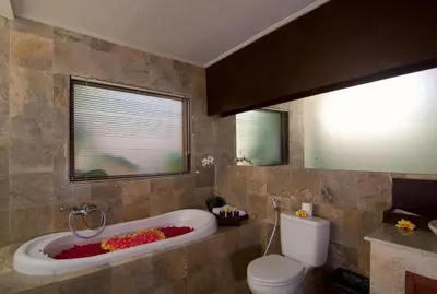 a bathroom with a tub and a toilet and a window at The Awan Villas Seminyak in Seminyak