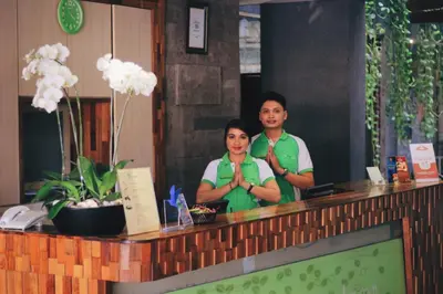 a man and woman standing behind a counter in a restaurant at Grandmas Plus Hotel Legian in Legian