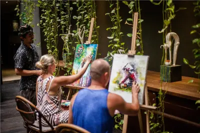 a group of people sitting around a table with paintings at Grandmas Plus Hotel Legian in Legian