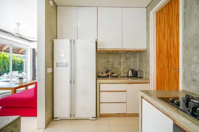 a kitchen with white cabinets and a refrigerator at Villa Love Umalas in Kerobokan