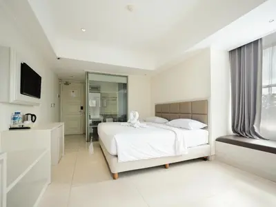 a white bedroom with a bed and a mirror at Alron Hotel Kuta in Kuta