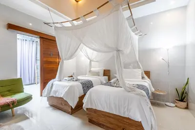 a bedroom with two beds and a canopy bed at Kubu Joglo Villa in Seminyak