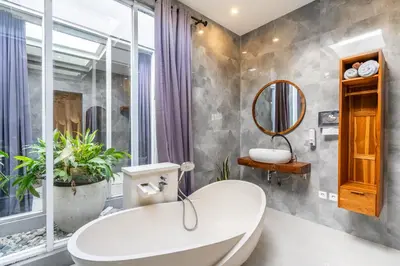 a bathroom with a white tub and a mirror at Kubu Joglo Villa in Seminyak