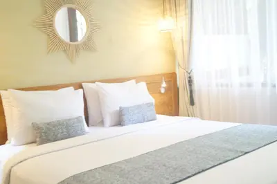 a bedroom with a large white bed with a mirror at Arana Suite in Legian