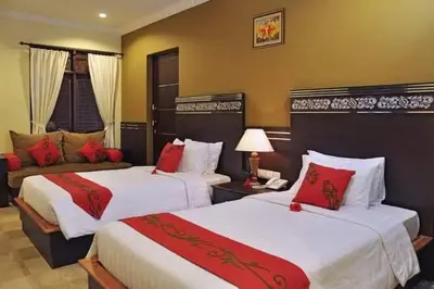 a hotel room with two beds and a couch at Alamanda Villa in Seminyak