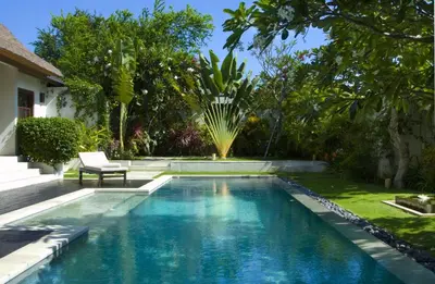 a swimming pool in a garden with a bench next to it at Villa Bali Asri in Seminyak