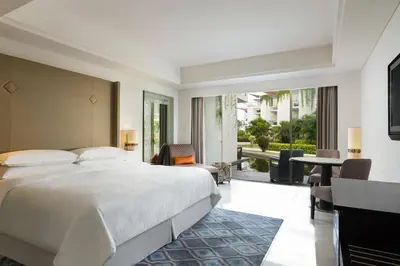 a bedroom with a large bed and a living room at Sheraton Bali Kuta Resort in Kuta