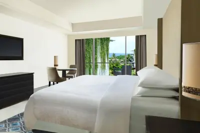 a bedroom with a large white bed and a window at Sheraton Bali Kuta Resort in Kuta