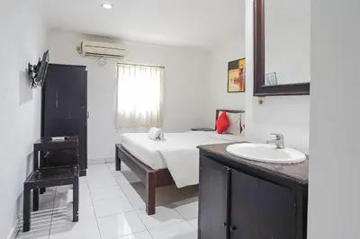 a bedroom with a bed with a sink and a mirror at Gana Inn Legian in Legian