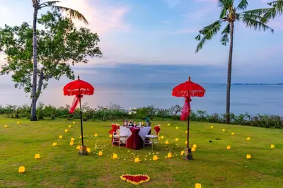 a table with chairs and red umbrellas in a field at AYANA Villas Bali in Jimbaran