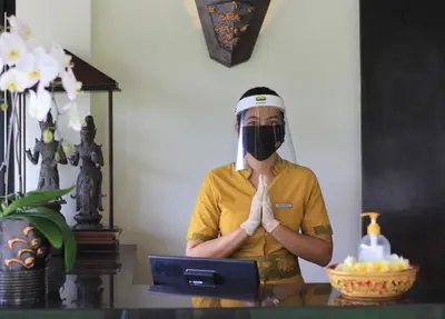 a woman wearing a mask and praying in front of a laptop at Villa Seminyak Estate & Spa - By Astadala in Seminyak