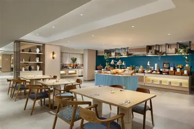 a restaurant with tables and chairs and a kitchen at Hilton Garden Inn Bali Nusa Dua in Nusa Dua